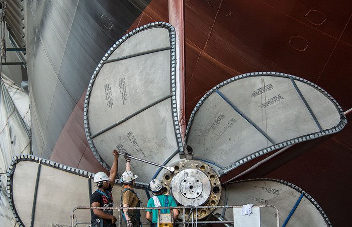 Các công nhân đang siết những con ốc trên một chân vịt của tàu USS Gerald R. Ford bằng một chiếc cần siết lực. Các công nhân đang siết những con ốc trên một chân vịt của tàu USS Gerald R. Ford bằng một chiếc cần siết lực.